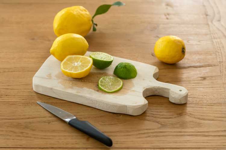sliced lemon beside knife on brown wooden chopping board